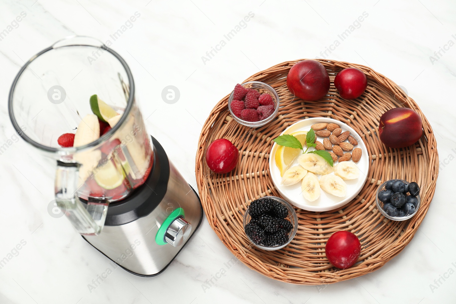 Photo of Blender and fresh ingredients on white marble table