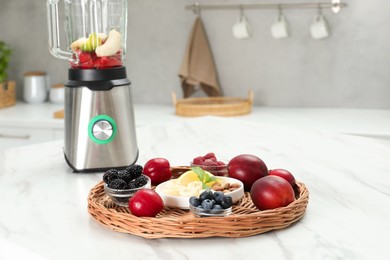 Photo of Blender and fresh ingredients on white marble table in kitchen