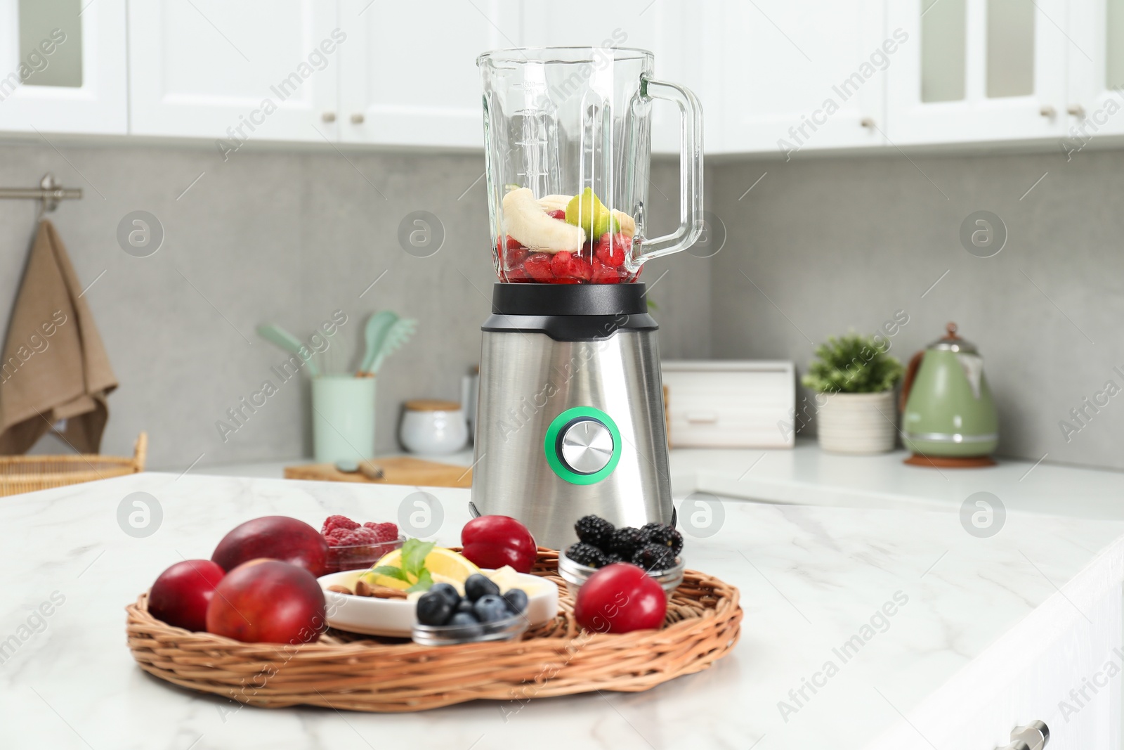 Photo of Blender and fresh ingredients on white marble table in kitchen