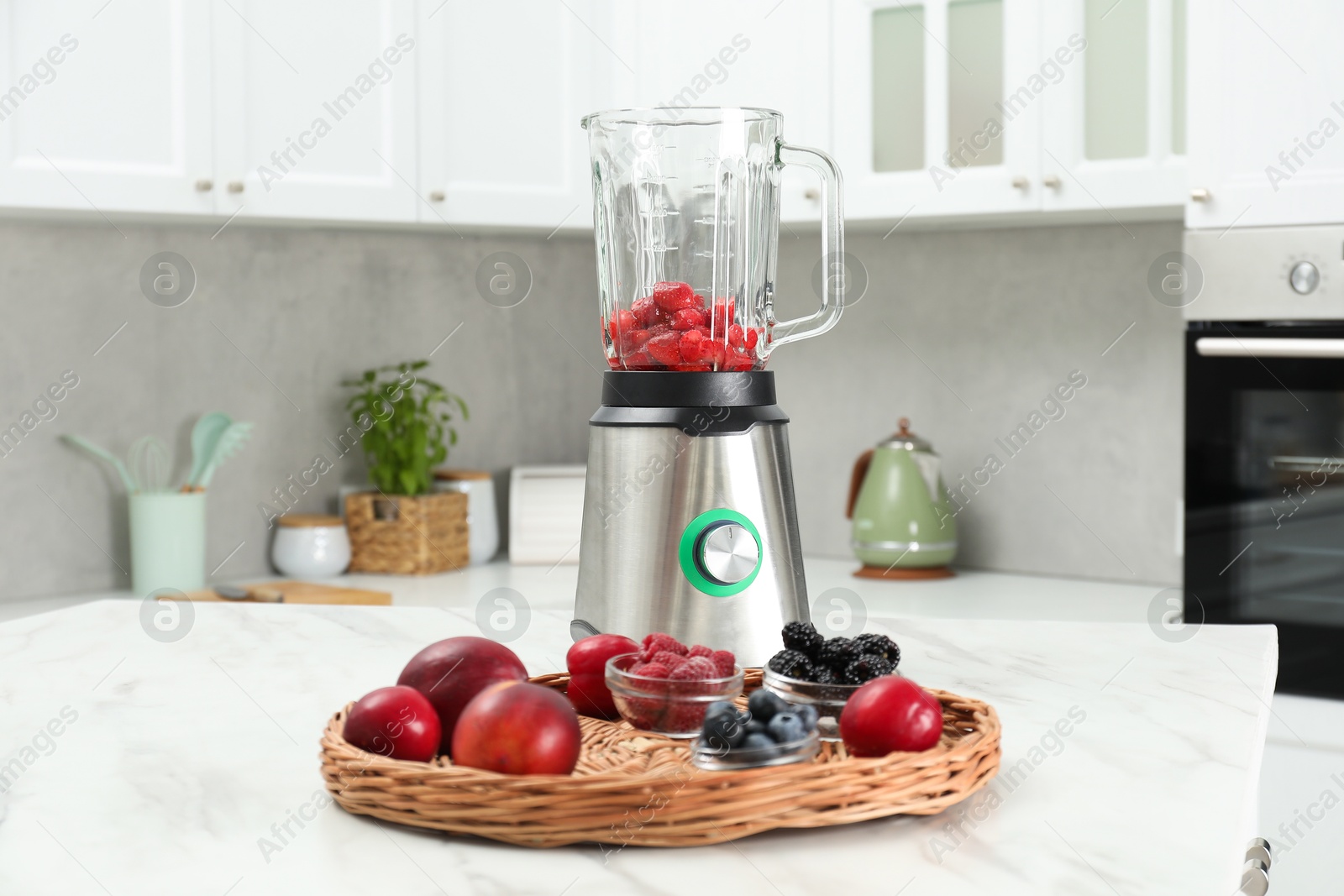 Photo of Blender and fresh ingredients on white marble table in kitchen