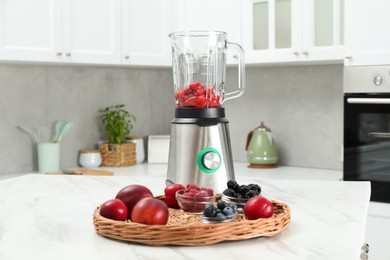 Photo of Blender and fresh ingredients on white marble table in kitchen