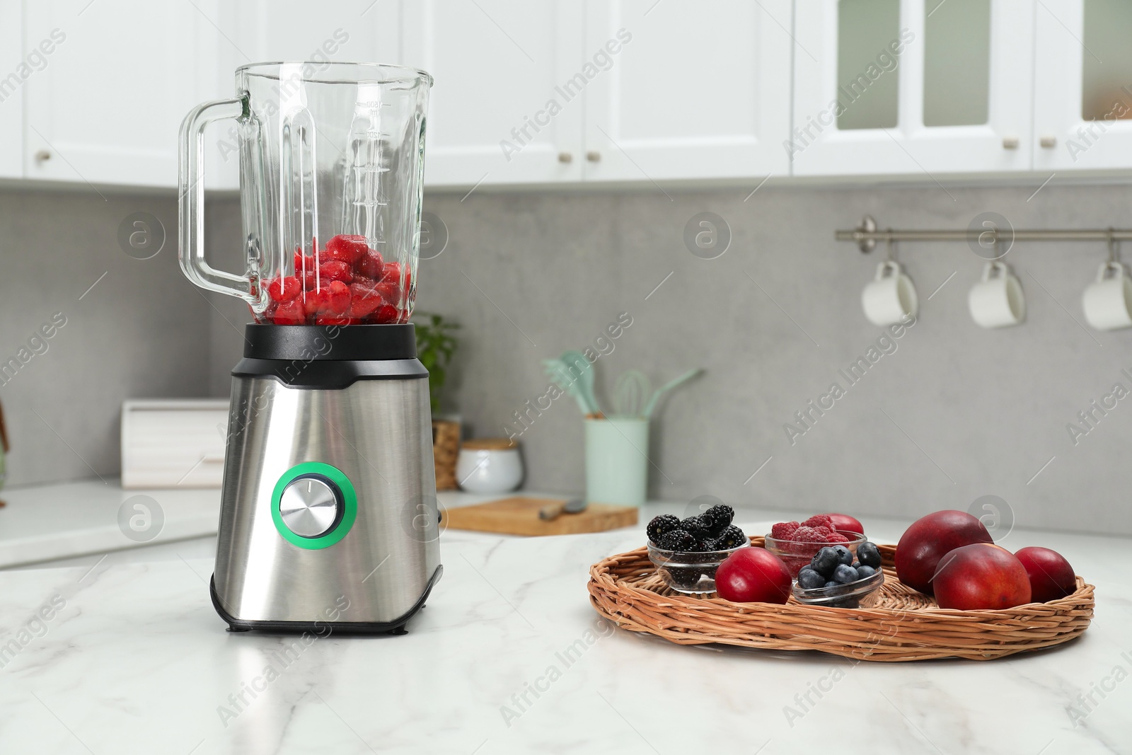 Photo of Blender and fresh ingredients on white marble table in kitchen