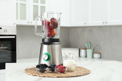 Blender and fresh ingredients on white marble table in kitchen