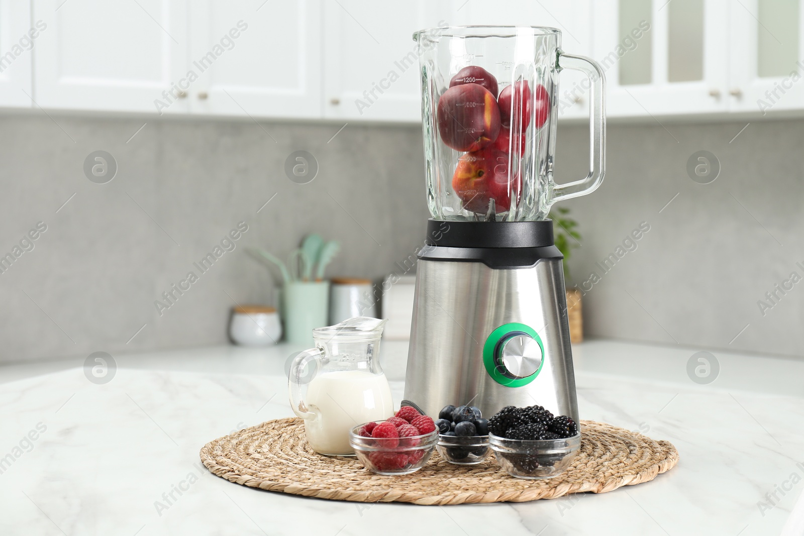 Photo of Blender and fresh ingredients on white marble table in kitchen