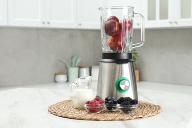 Blender and fresh ingredients on white marble table in kitchen