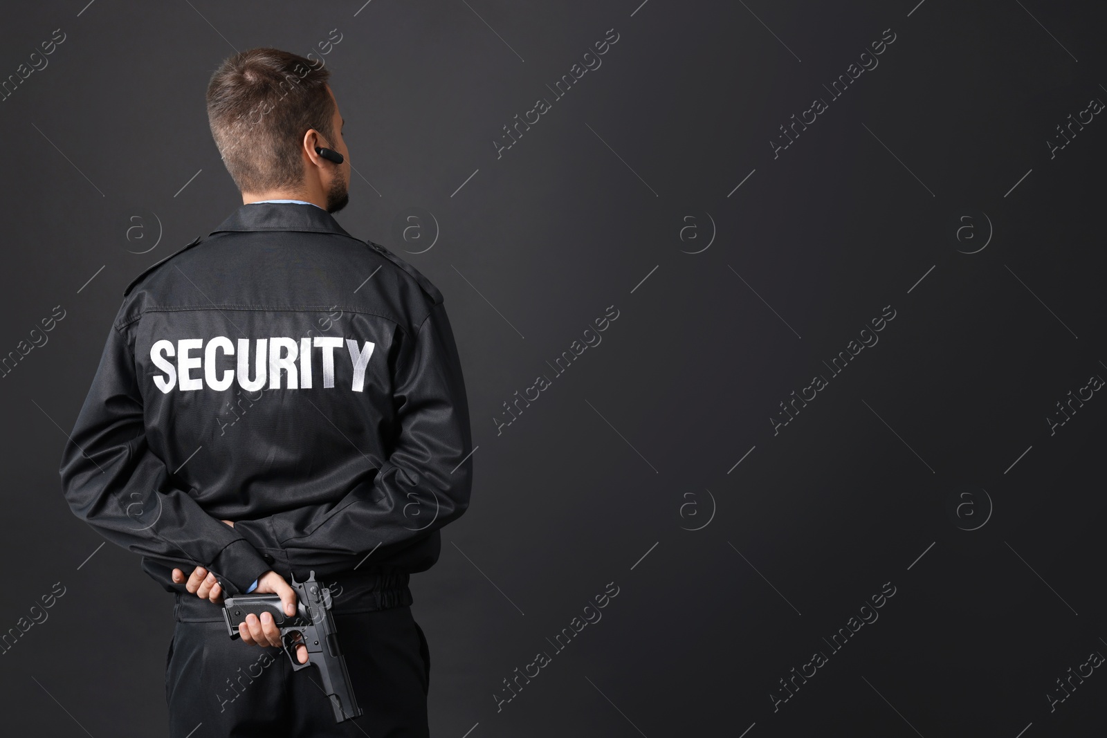 Photo of Security guard in uniform with gun on black background, back view. Space for text