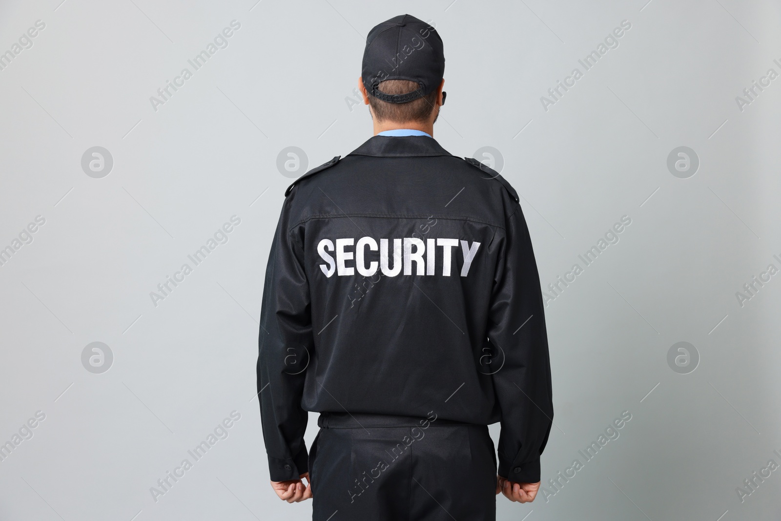 Photo of Security guard in uniform on grey background, back view