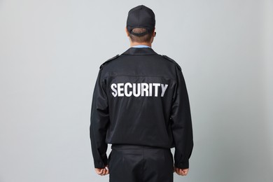 Security guard in uniform on grey background, back view