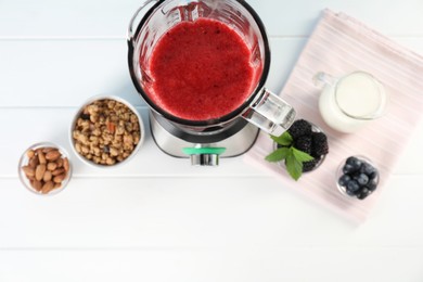 Photo of Blender with mixture of ingredients and other fresh products on white wooden table, top view