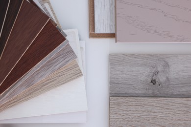 Photo of Different samples of wooden flooring on white table, top view