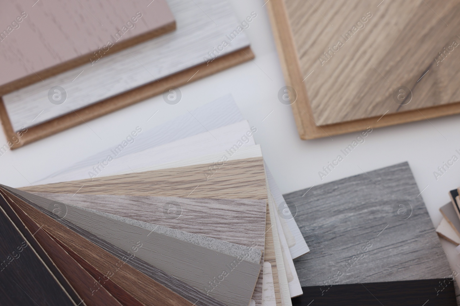 Photo of Different samples of wooden flooring on white table, above view