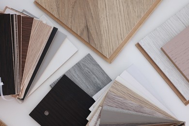 Photo of Different samples of wooden flooring on white table, top view