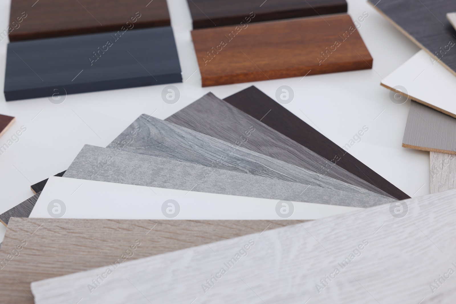 Photo of Different samples of wooden flooring on white table, closeup