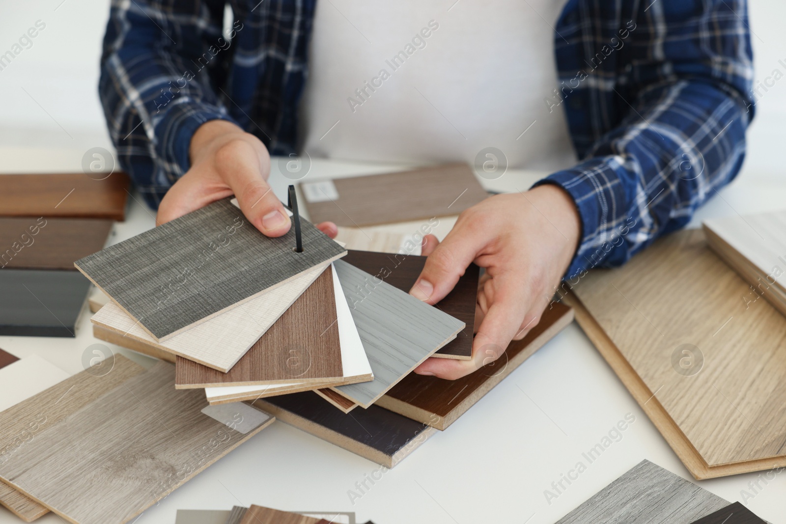 Photo of Man choosing wooden flooring among different samples at table, closeup