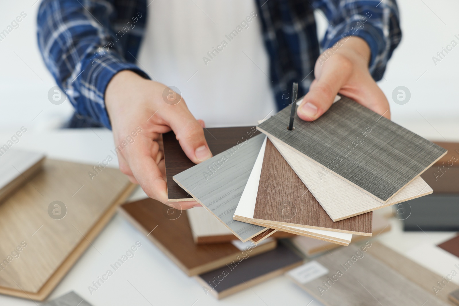 Photo of Man choosing wooden flooring among different samples at table, closeup