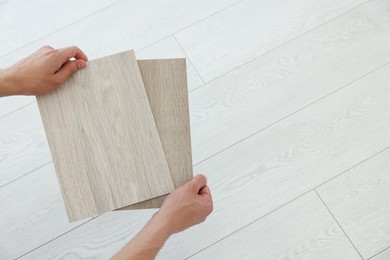 Photo of Man with samples of wooden flooring indoors, above view. Space for text