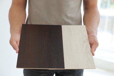 Photo of Man with samples of wooden flooring indoors, closeup