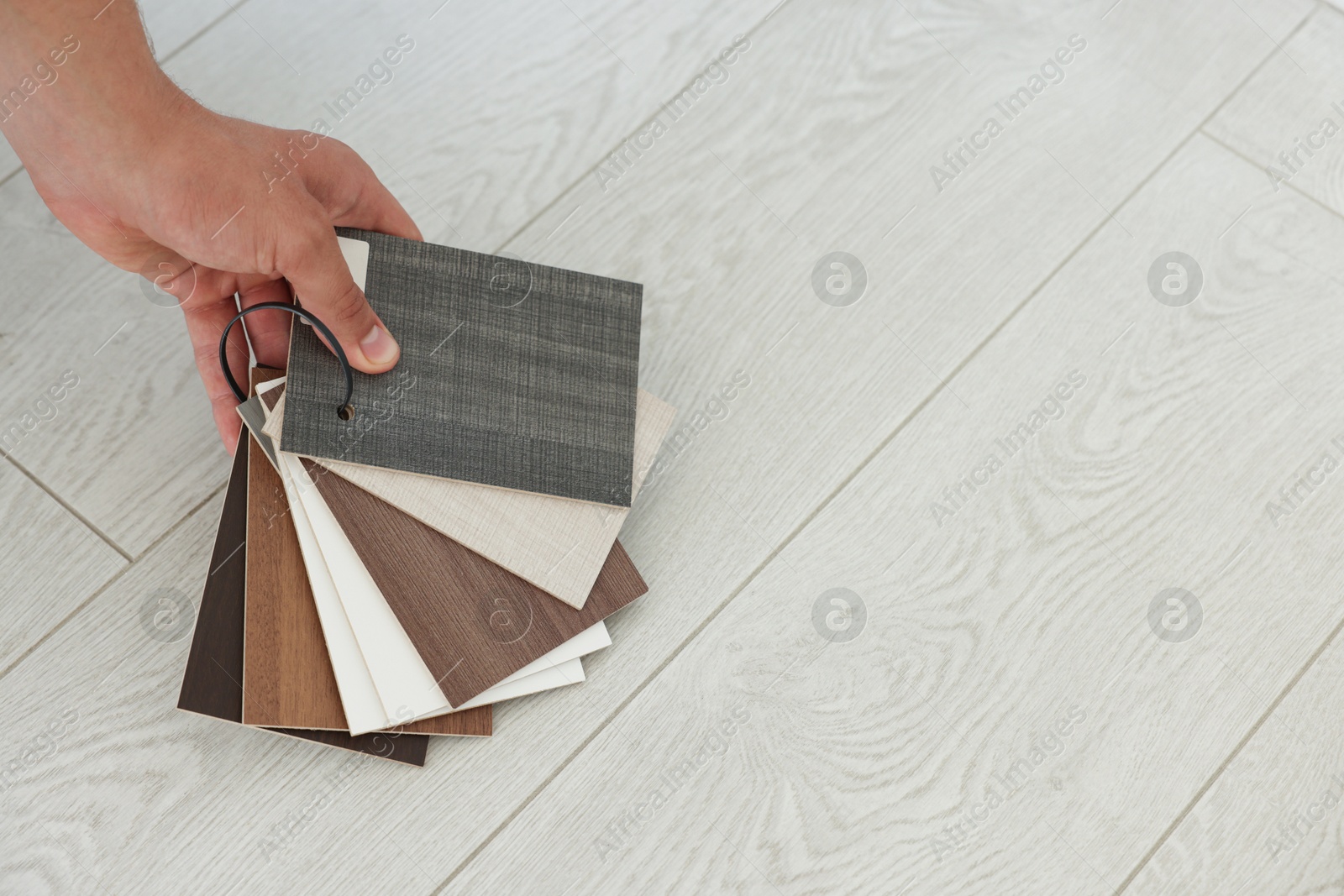 Photo of Man with samples of wooden flooring indoors, closeup. Space for text