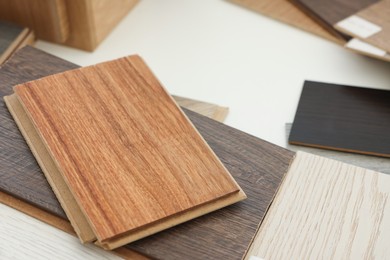 Photo of Different samples of wooden flooring on white table, closeup