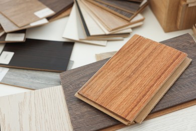 Photo of Different samples of wooden flooring on white table, closeup