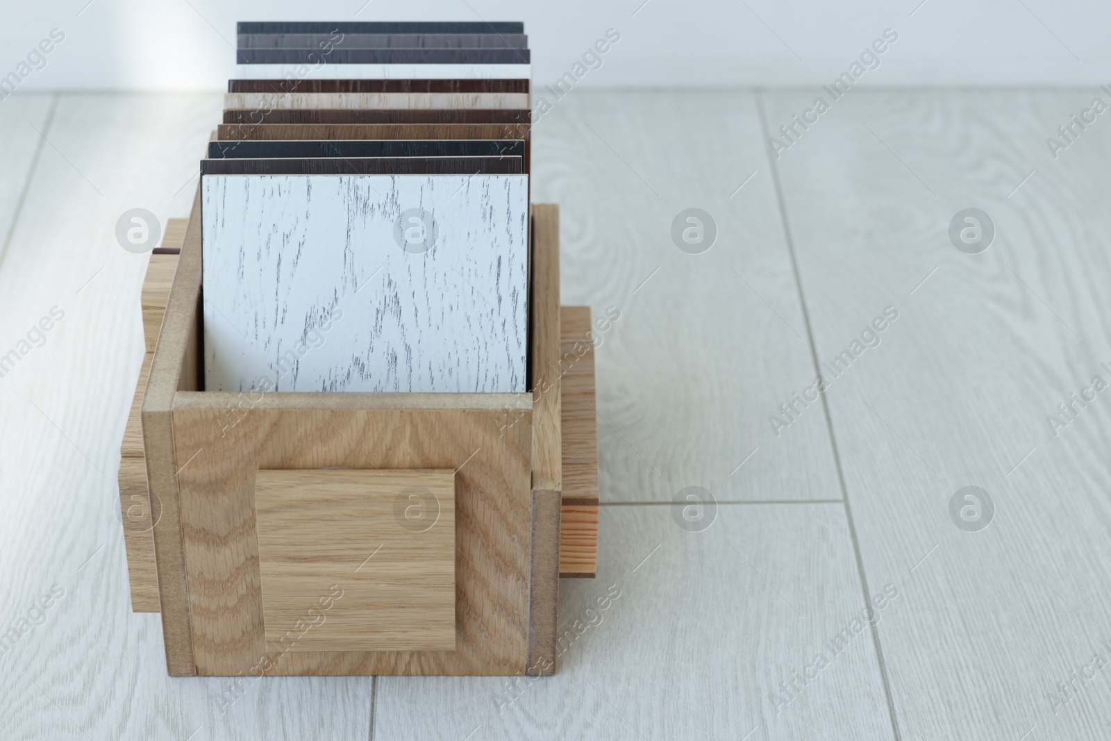 Photo of Different samples of wooden flooring in crate indoors, space for text