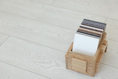 Photo of Different samples of wooden flooring in crate indoors, space for text