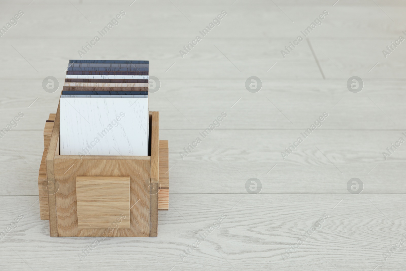 Photo of Different samples of wooden flooring in crate indoors, space for text