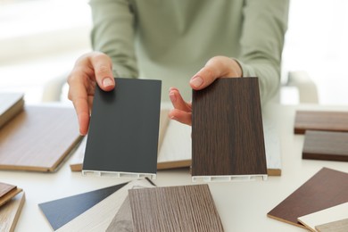 Photo of Woman choosing wooden flooring among different samples at table, closeup