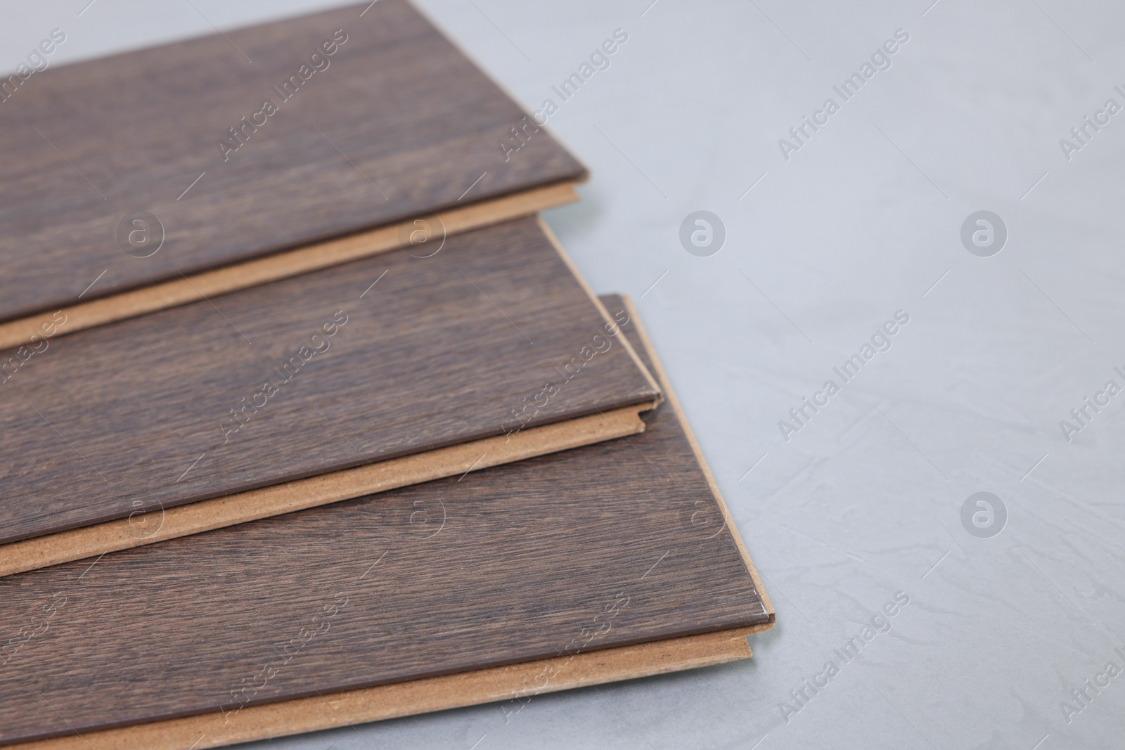 Photo of Laminate flooring pieces on grey textured surface, closeup