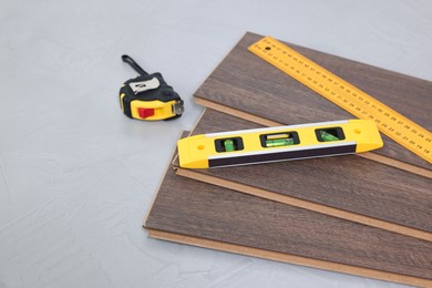 Photo of Different measuring tools and laminate flooring pieces on grey textured surface