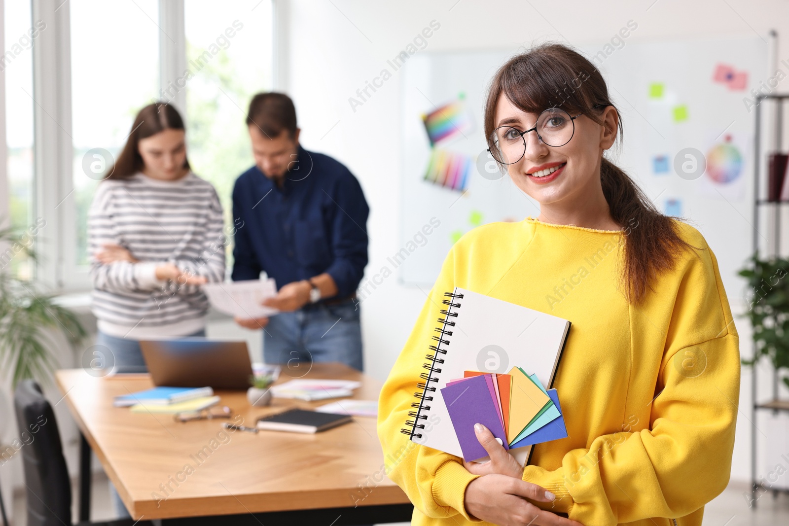 Photo of Portrait of happy young designer with notebook in office