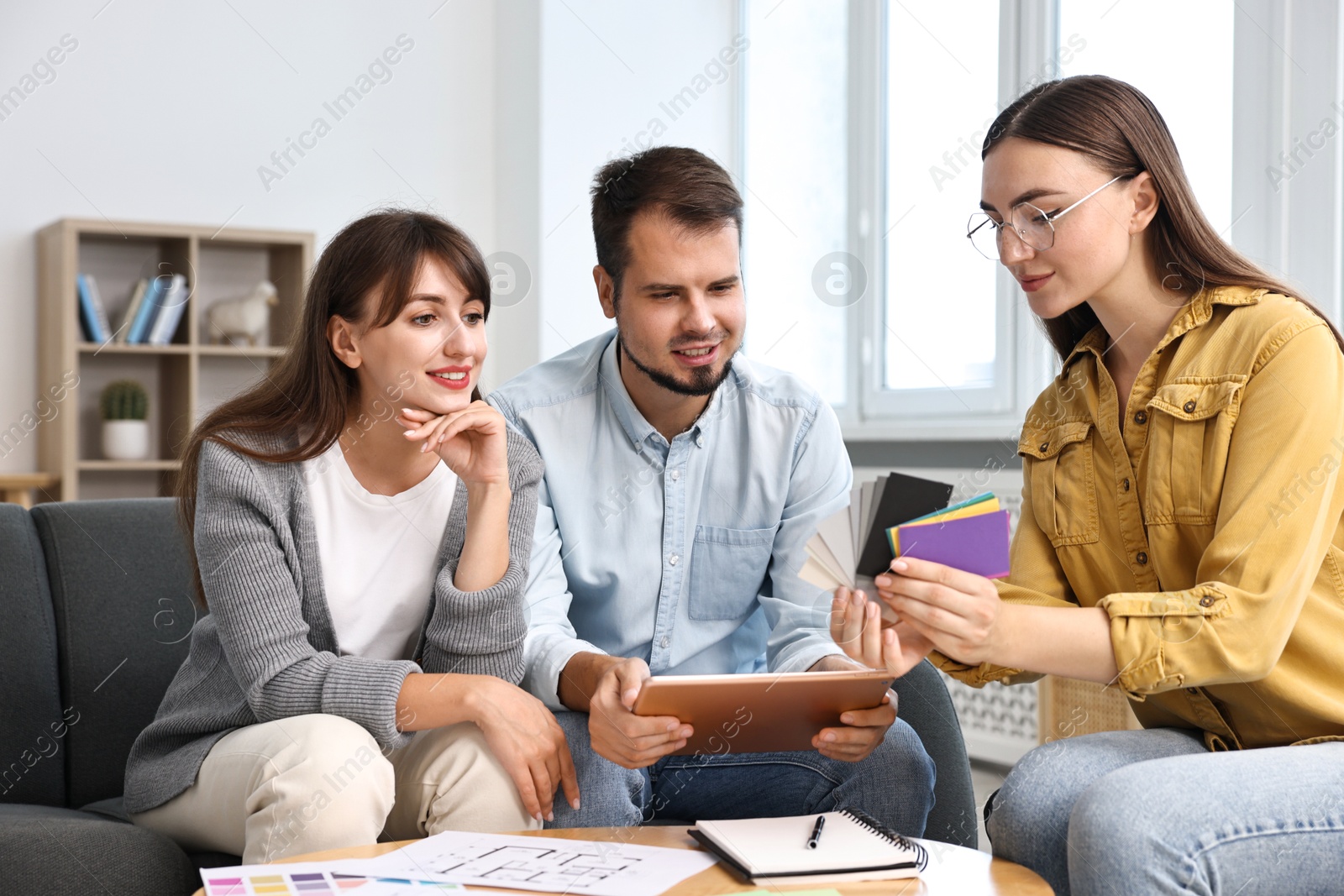 Photo of Designer discussing project with clients at table in office