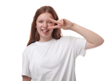 Teenage girl showing her tongue and v-sign on white background