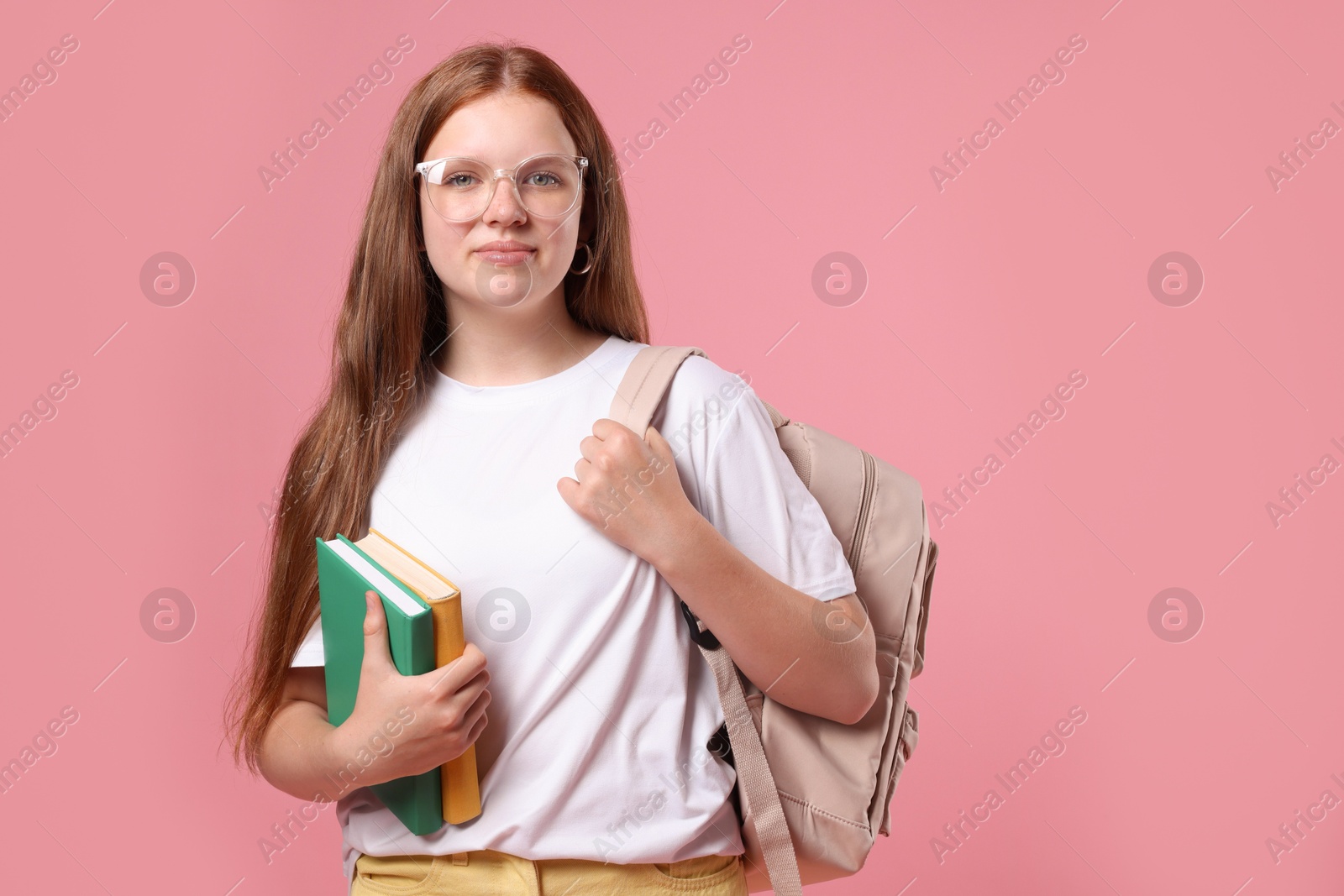 Photo of Teenage girl with backpack and books on pink background