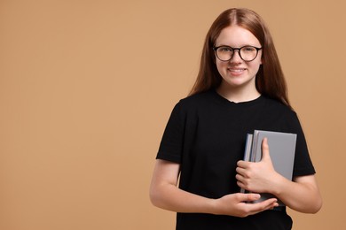 Teenage girl with books on beige background, space for text