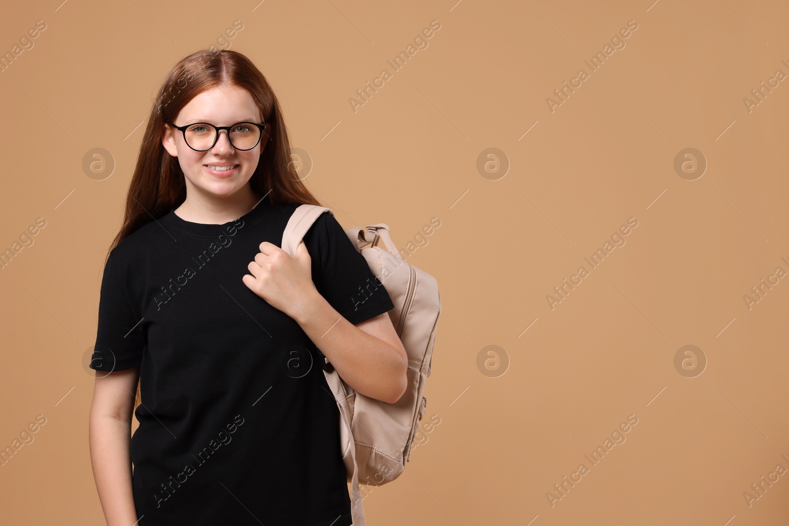 Photo of Teenage girl with backpack on beige background, space for text