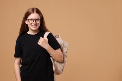 Teenage girl with backpack on beige background, space for text