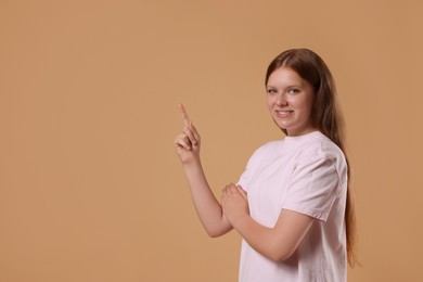 Portrait of teenage girl on beige background, space for text