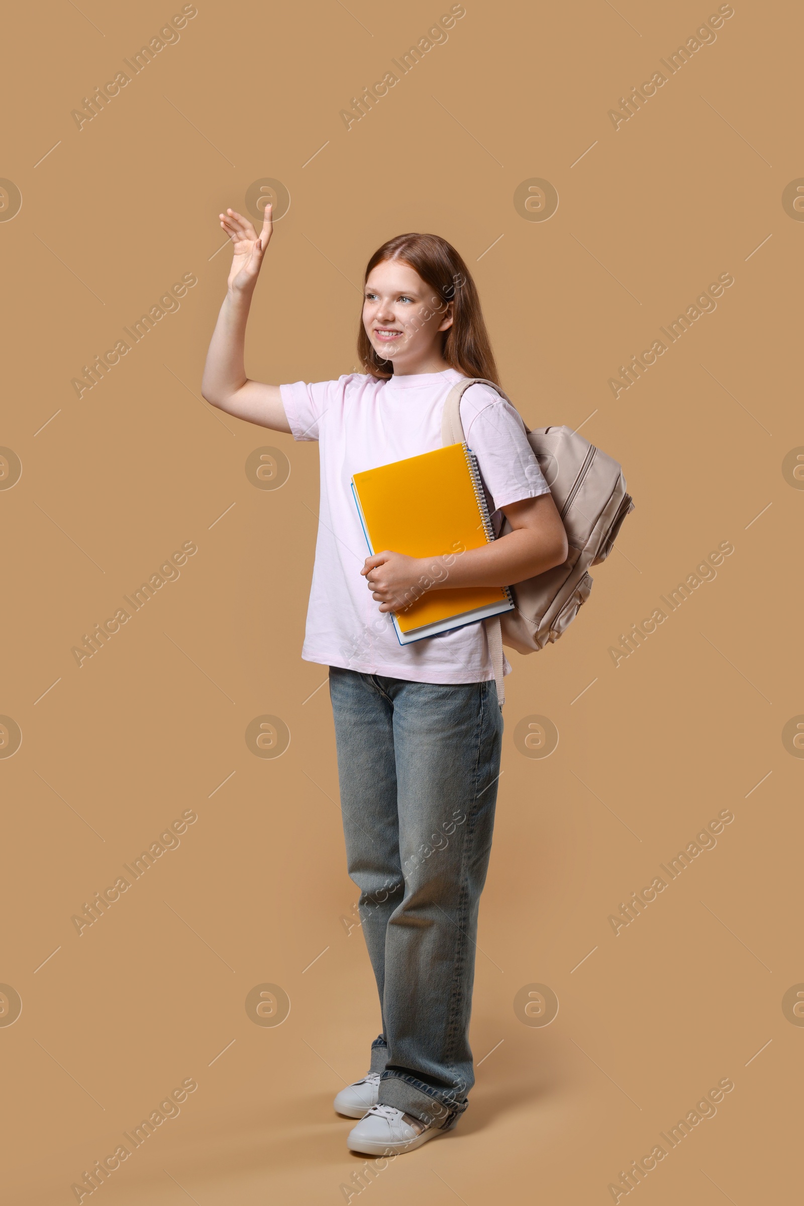 Photo of Teenage girl with backpack and books on beige background