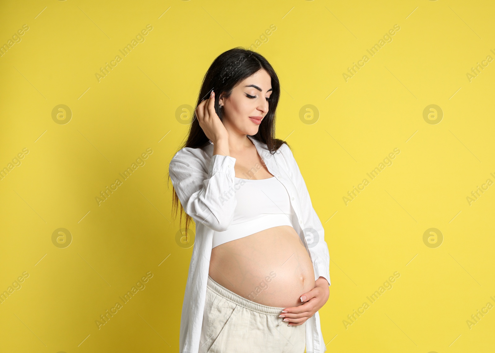 Photo of Portrait of beautiful pregnant woman on yellow background