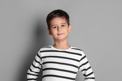 Portrait of cute little boy on grey background