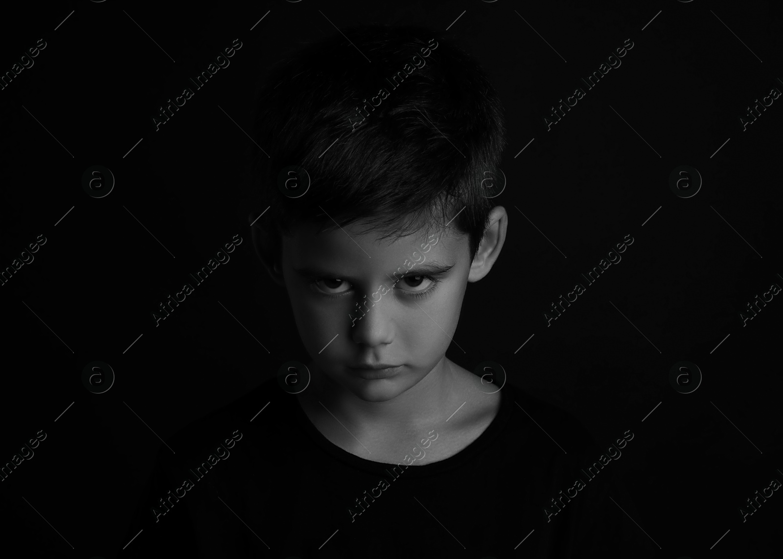 Photo of Angry little boy on dark background. Black and white effect