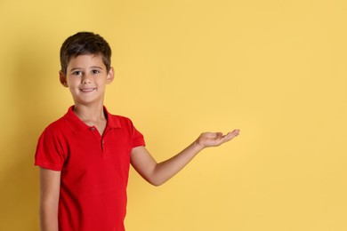 Photo of Portrait of cute little boy on yellow background, space for text