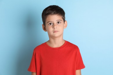 Photo of Portrait of cute little boy on light blue background