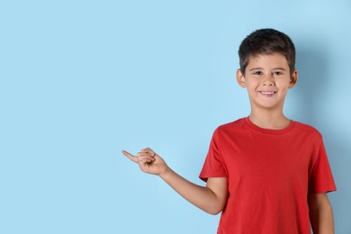 Photo of Portrait of cute little boy on light blue background, space for text