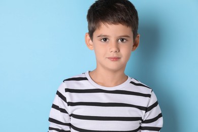 Photo of Portrait of cute little boy on light blue background