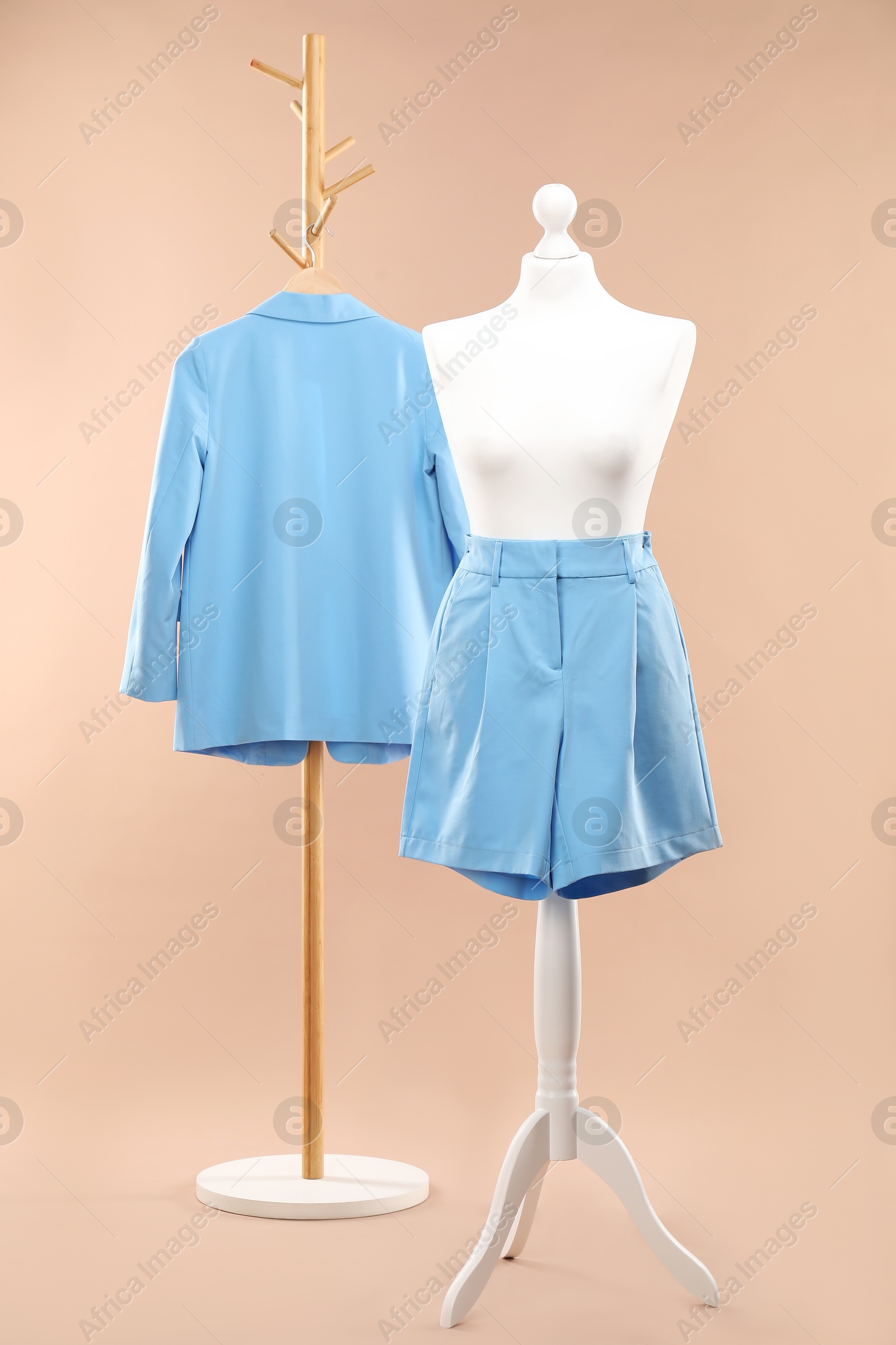 Photo of One female mannequin with shorts and rack with jacket against beige background