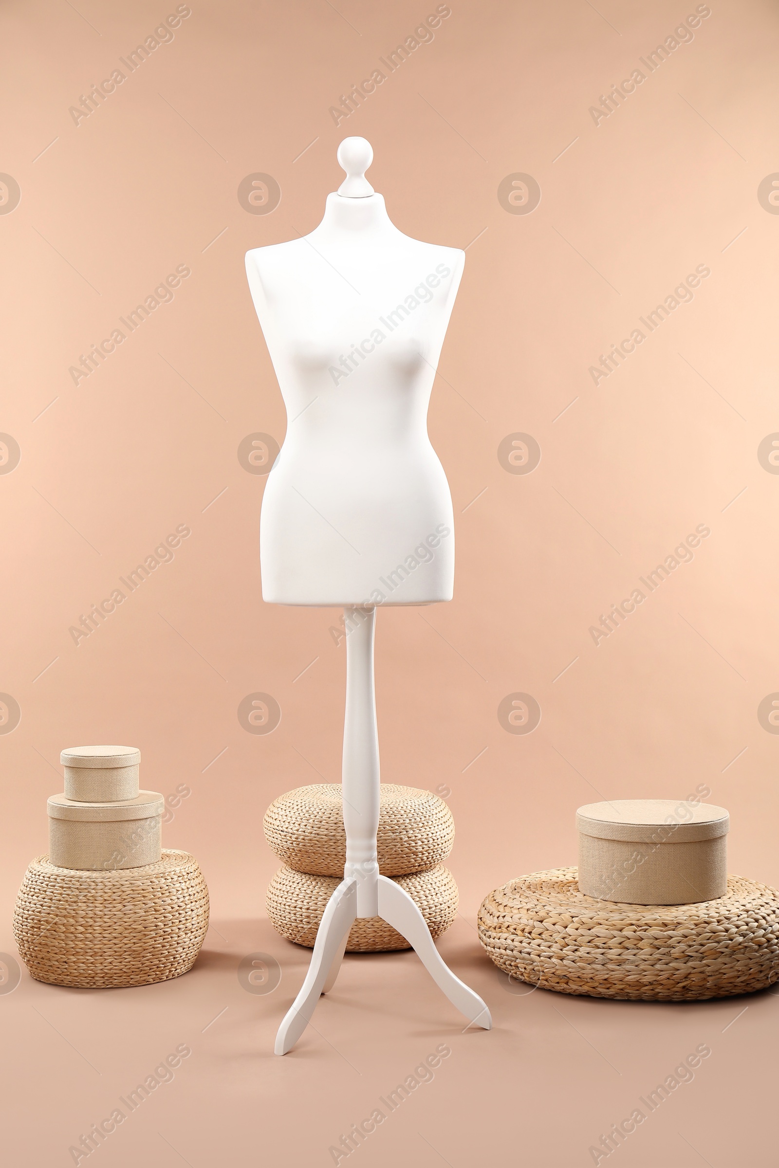 Photo of One female mannequin, poufs and boxes on beige background