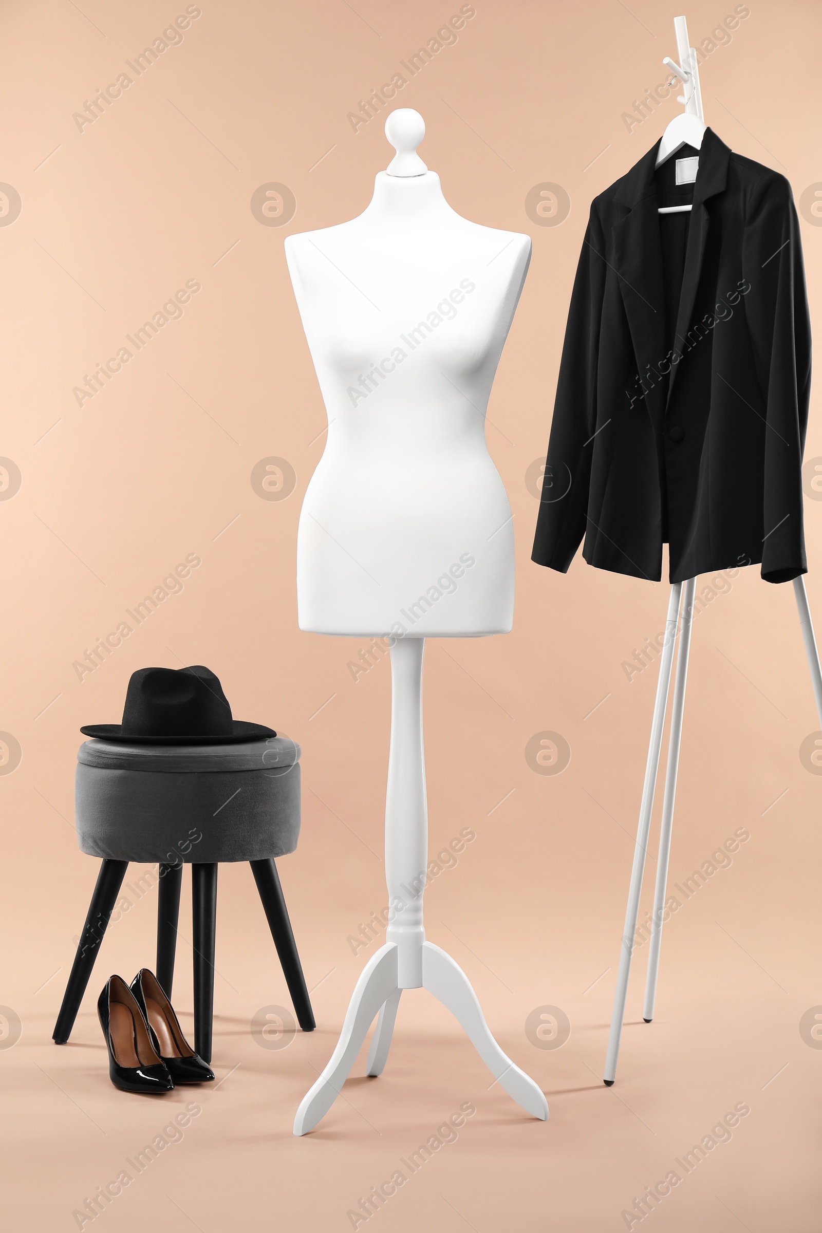 Photo of Female mannequin, hat, ottoman, rack, jacket and shoes on beige background