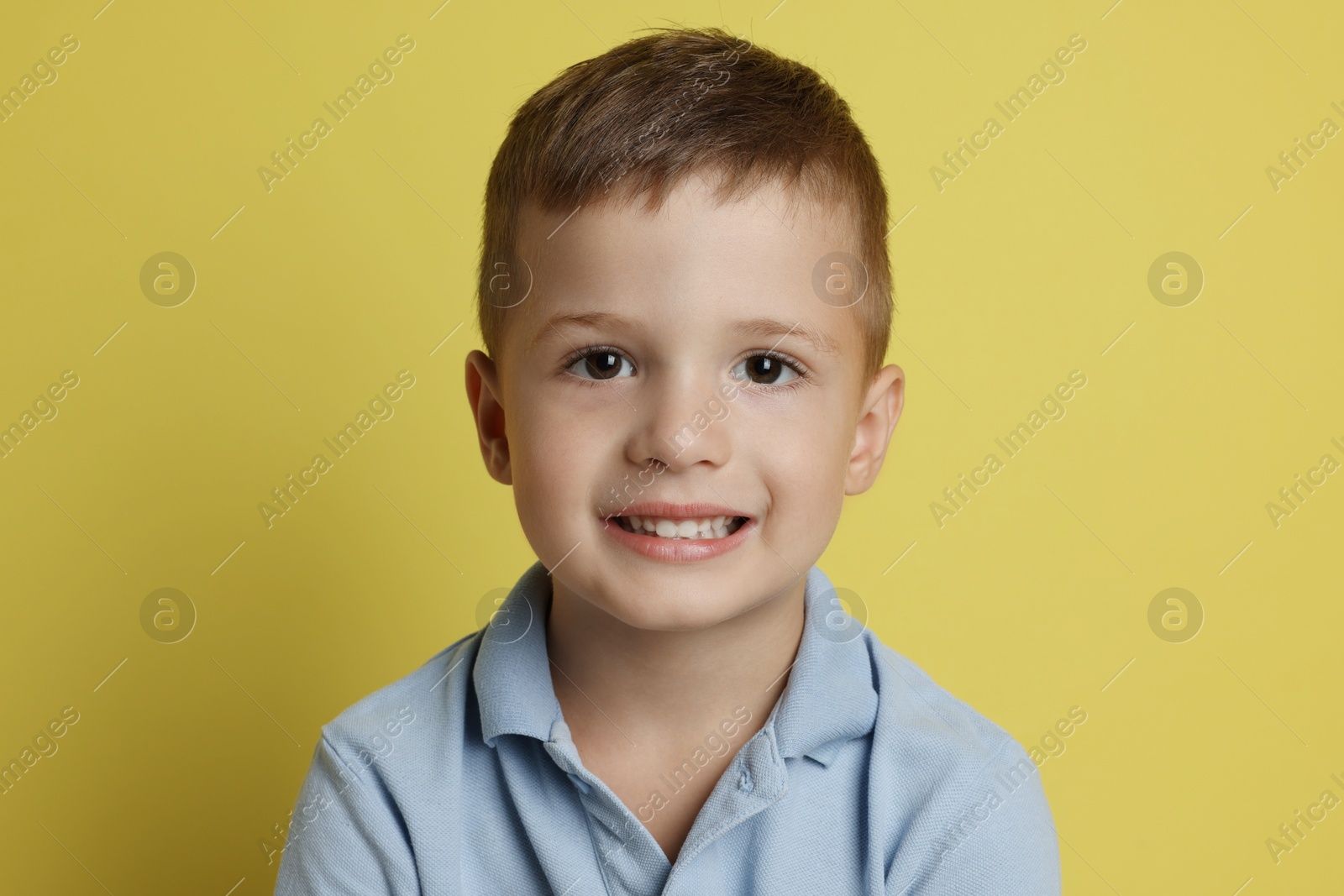 Photo of Portrait of cute little boy on yellow background